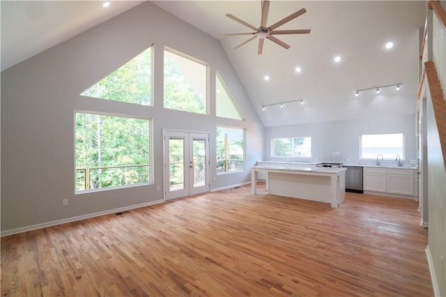 unfurnished living room featuring ceiling fan, french doors, high vaulted ceiling, light hardwood / wood-style floors, and track lighting