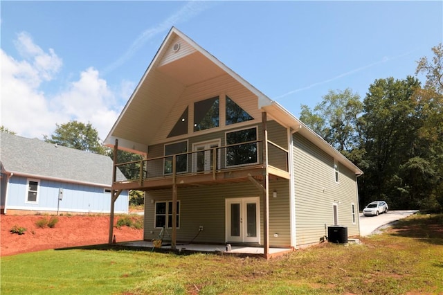 rear view of property with a balcony, a yard, a patio, and french doors