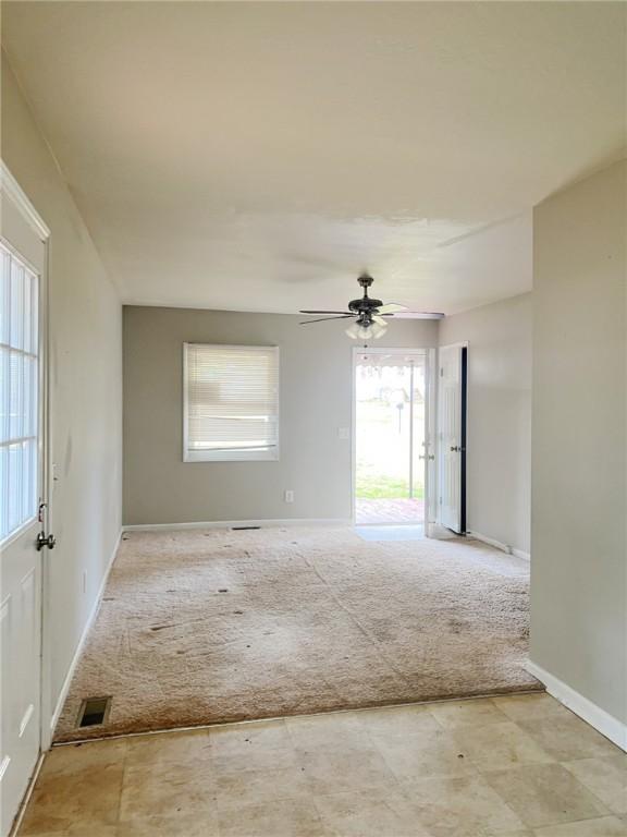 unfurnished room with ceiling fan and carpet