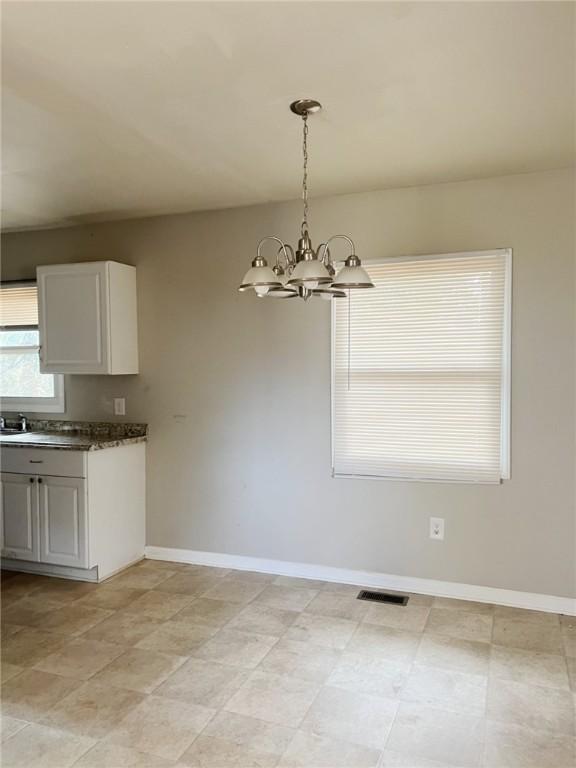 unfurnished dining area featuring sink and a chandelier