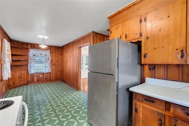 kitchen featuring carpet flooring, stainless steel fridge, electric range, and wood walls