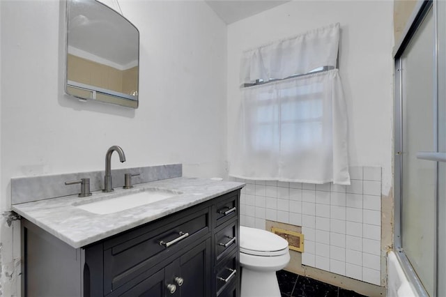 full bathroom with vanity, toilet, tile walls, and combined bath / shower with glass door