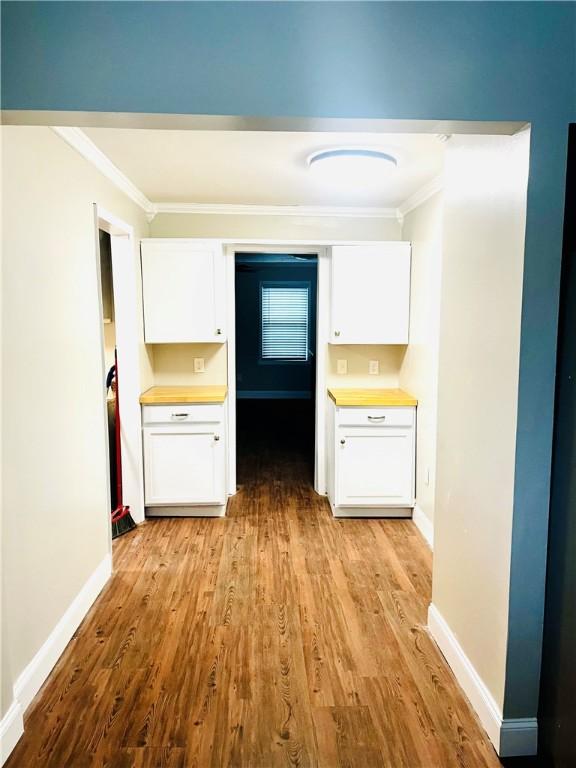 kitchen with white cabinets, light wood-type flooring, and ornamental molding