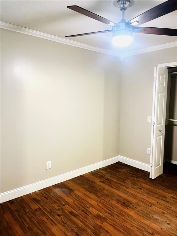 unfurnished room featuring dark hardwood / wood-style flooring, ceiling fan, and ornamental molding