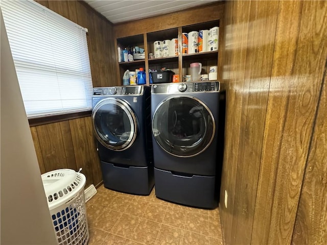 clothes washing area with separate washer and dryer and wooden walls