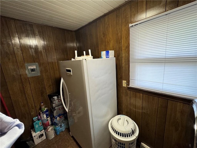 interior space with tile patterned flooring, fridge, and wooden walls