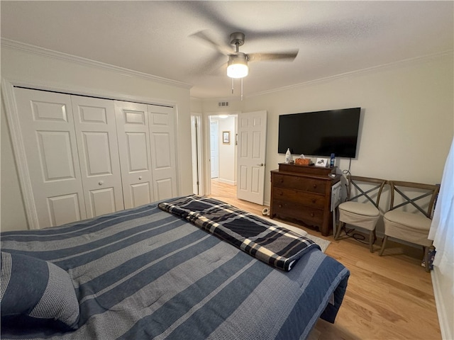 bedroom with ceiling fan, a closet, crown molding, and light hardwood / wood-style flooring