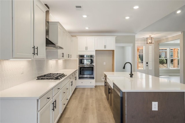 kitchen featuring stainless steel appliances, white cabinetry, a center island with sink, and sink