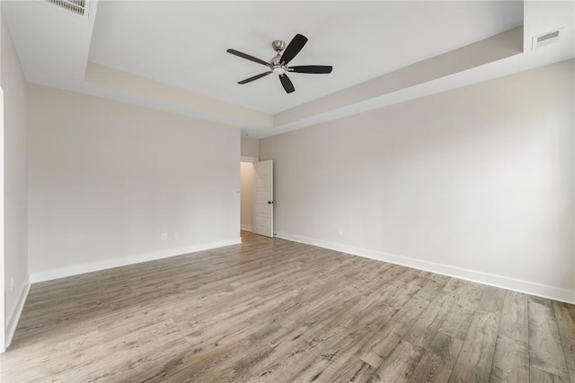 empty room featuring a raised ceiling, ceiling fan, and wood-type flooring