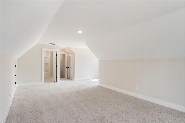 additional living space featuring light colored carpet and vaulted ceiling