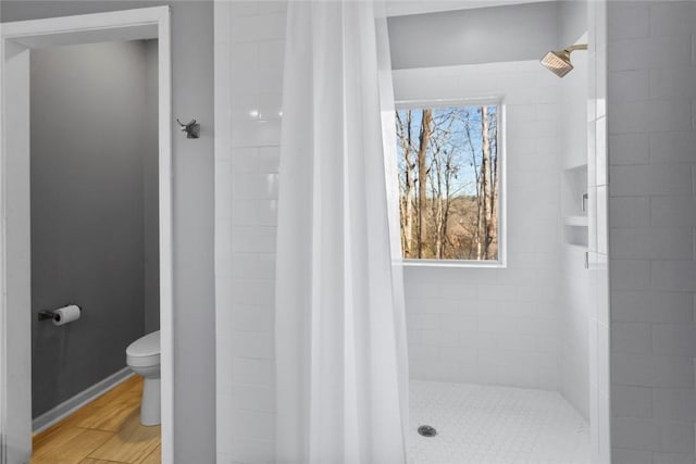 bathroom featuring hardwood / wood-style floors, toilet, and a tile shower