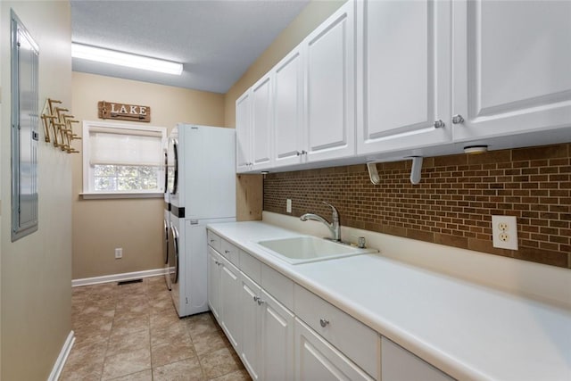 clothes washing area featuring cabinets, stacked washer / drying machine, and sink