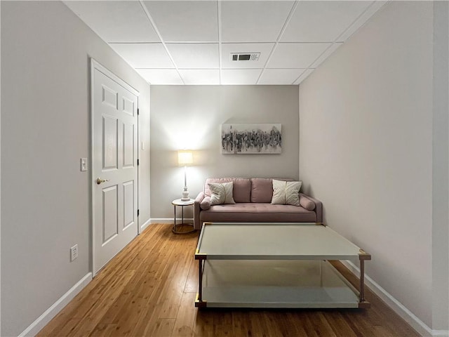 sitting room with hardwood / wood-style floors and a drop ceiling