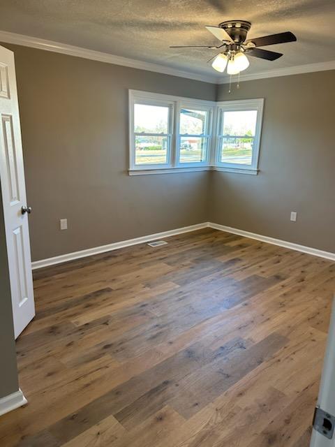 spare room with dark hardwood / wood-style flooring, crown molding, and a textured ceiling