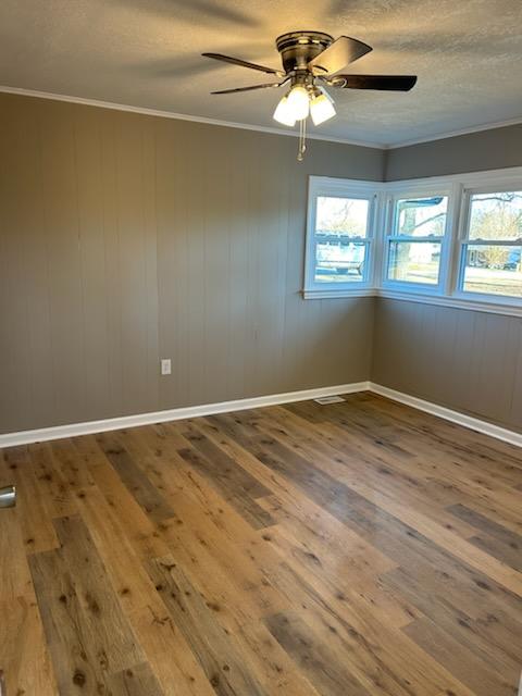 spare room with wood-type flooring, a healthy amount of sunlight, and crown molding