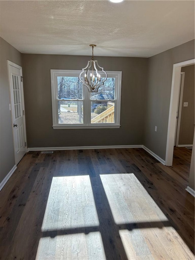 unfurnished dining area with dark wood-type flooring and a chandelier