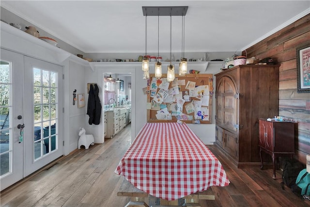 dining area featuring crown molding, french doors, wood-type flooring, and wooden walls