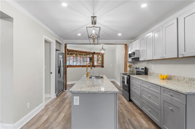 kitchen featuring stainless steel appliances, crown molding, sink, pendant lighting, and an island with sink