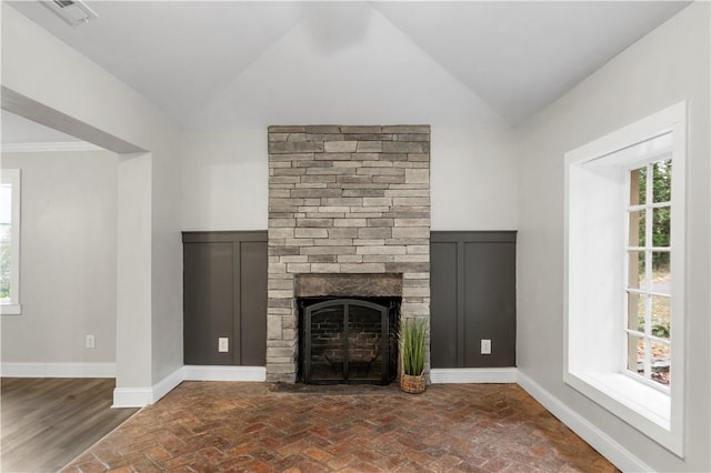 unfurnished living room with a wealth of natural light, a fireplace, crown molding, and vaulted ceiling