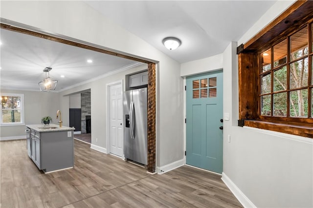 interior space featuring stainless steel refrigerator with ice dispenser, gray cabinetry, pendant lighting, a fireplace, and hardwood / wood-style floors