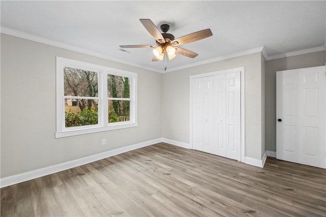 unfurnished bedroom with ceiling fan, wood-type flooring, crown molding, and a closet