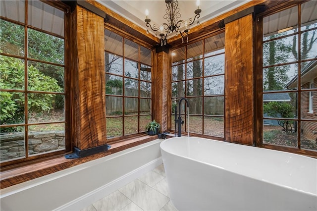 bathroom with tile patterned flooring, a notable chandelier, a tub, and a wealth of natural light