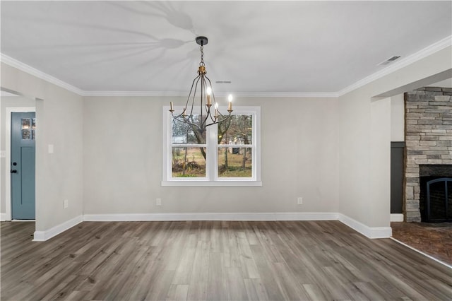 unfurnished dining area featuring a fireplace, wood-type flooring, a chandelier, and ornamental molding