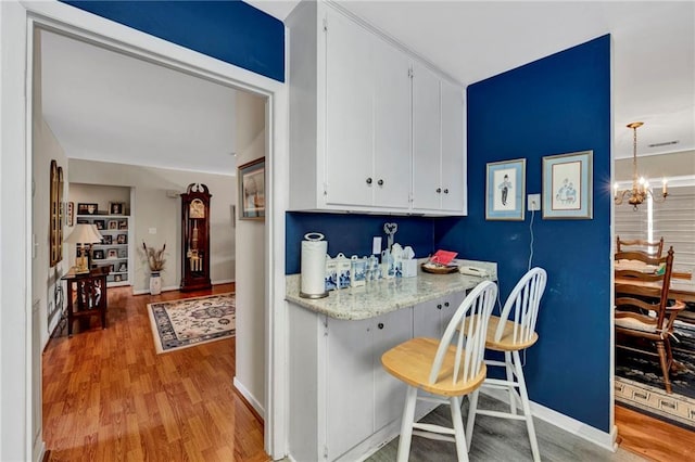 kitchen with a chandelier, white cabinetry, hanging light fixtures, and light wood-type flooring