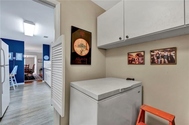 clothes washing area with cabinets and light hardwood / wood-style flooring