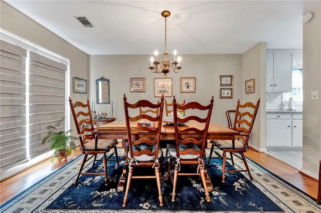 dining space with hardwood / wood-style flooring and a notable chandelier