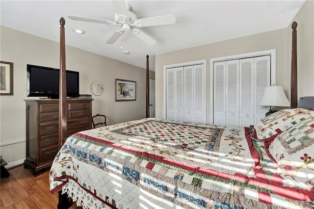 bedroom featuring hardwood / wood-style floors, ceiling fan, and multiple closets