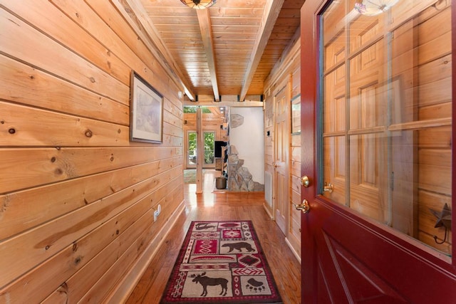 interior space with hardwood / wood-style floors, beam ceiling, wooden ceiling, and wooden walls