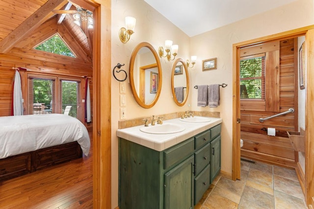 bathroom featuring ceiling fan, lofted ceiling, toilet, wooden walls, and vanity