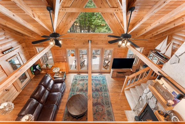 unfurnished living room featuring wood-type flooring, beam ceiling, ceiling fan, and wood ceiling