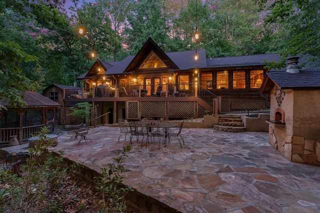 back house at dusk featuring a gazebo and a patio