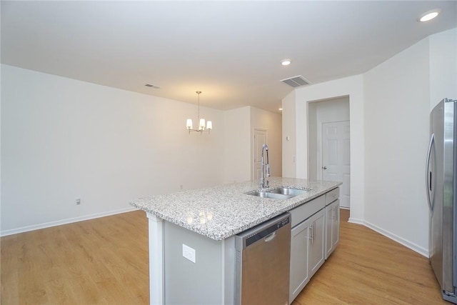 kitchen with stainless steel appliances, sink, pendant lighting, a notable chandelier, and an island with sink