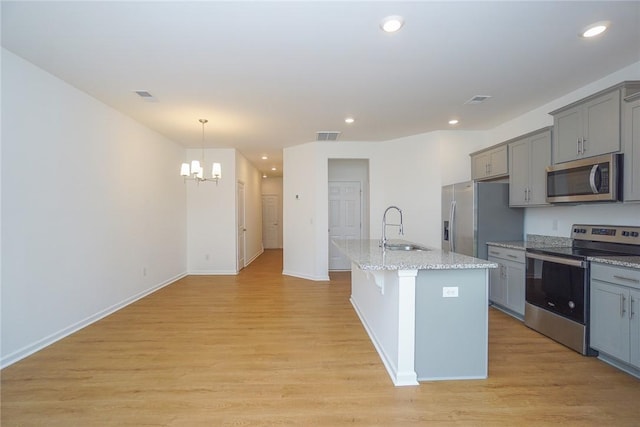 kitchen featuring sink, stainless steel appliances, an inviting chandelier, an island with sink, and light hardwood / wood-style floors