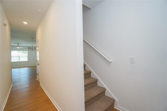 stairway with wood-type flooring and ceiling fan