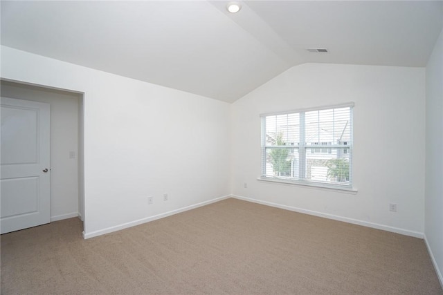 spare room featuring light carpet and lofted ceiling