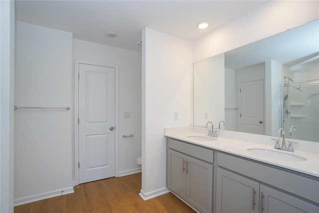 bathroom with hardwood / wood-style flooring, vanity, toilet, and a shower with door