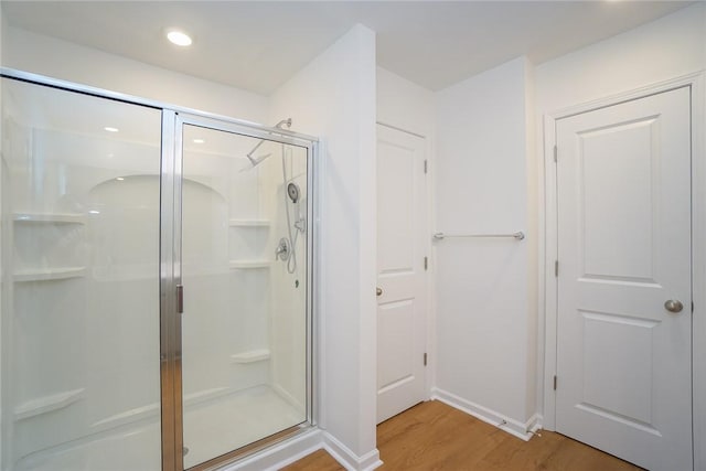 bathroom with hardwood / wood-style flooring and a shower with shower door