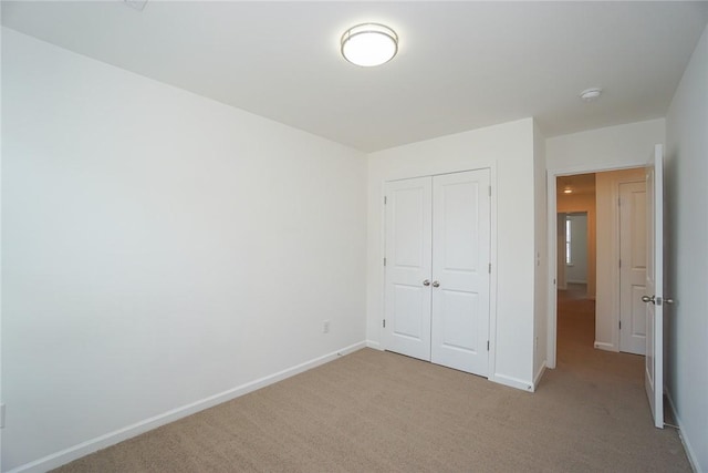 unfurnished bedroom featuring light carpet and a closet