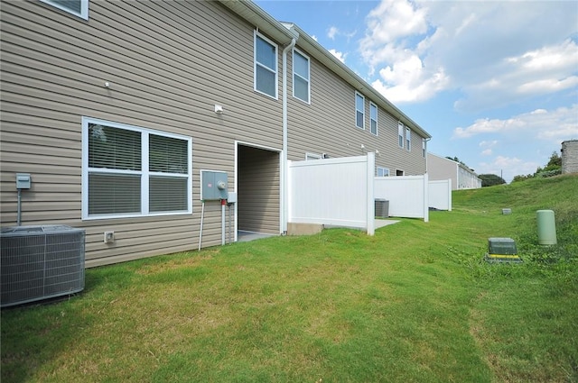 rear view of property with a lawn and cooling unit