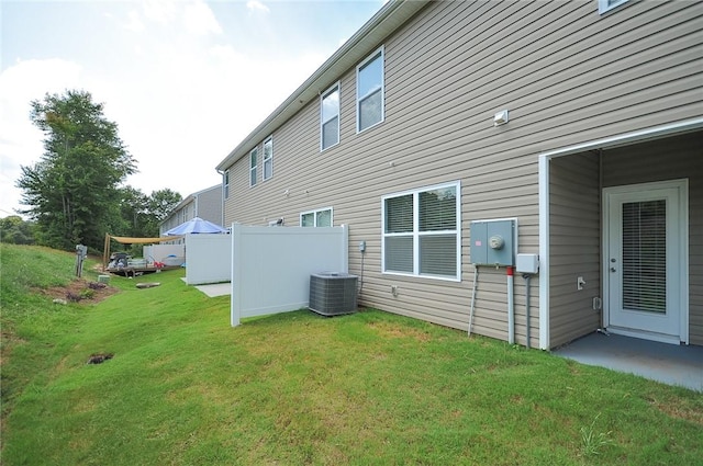 rear view of property with central AC and a yard