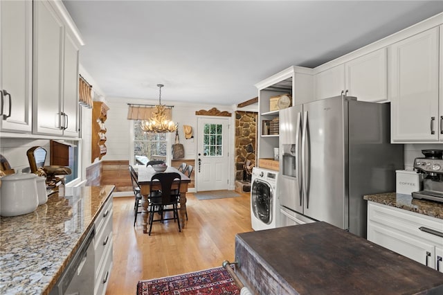 kitchen with white cabinets, appliances with stainless steel finishes, washer / clothes dryer, and a notable chandelier