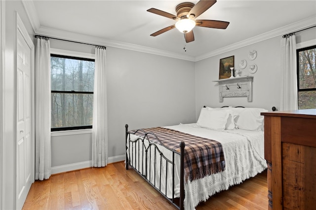 bedroom featuring ceiling fan, light hardwood / wood-style floors, crown molding, and a closet