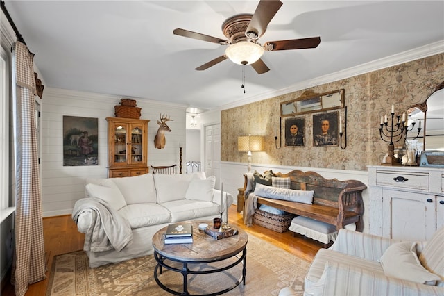 living room with ceiling fan, crown molding, wooden walls, and light hardwood / wood-style flooring