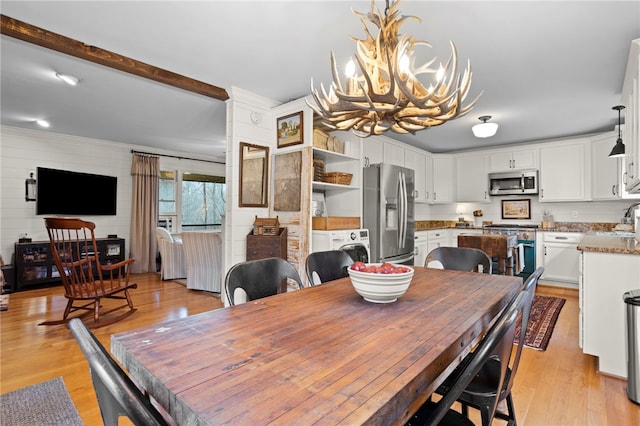 dining space featuring beamed ceiling, a notable chandelier, light wood-type flooring, and sink