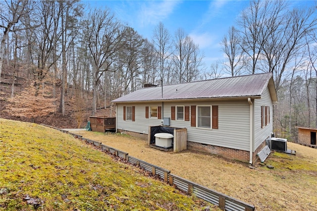 exterior space with cooling unit, a deck, and a front yard