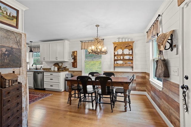 dining space featuring a chandelier, wood walls, plenty of natural light, and light hardwood / wood-style floors